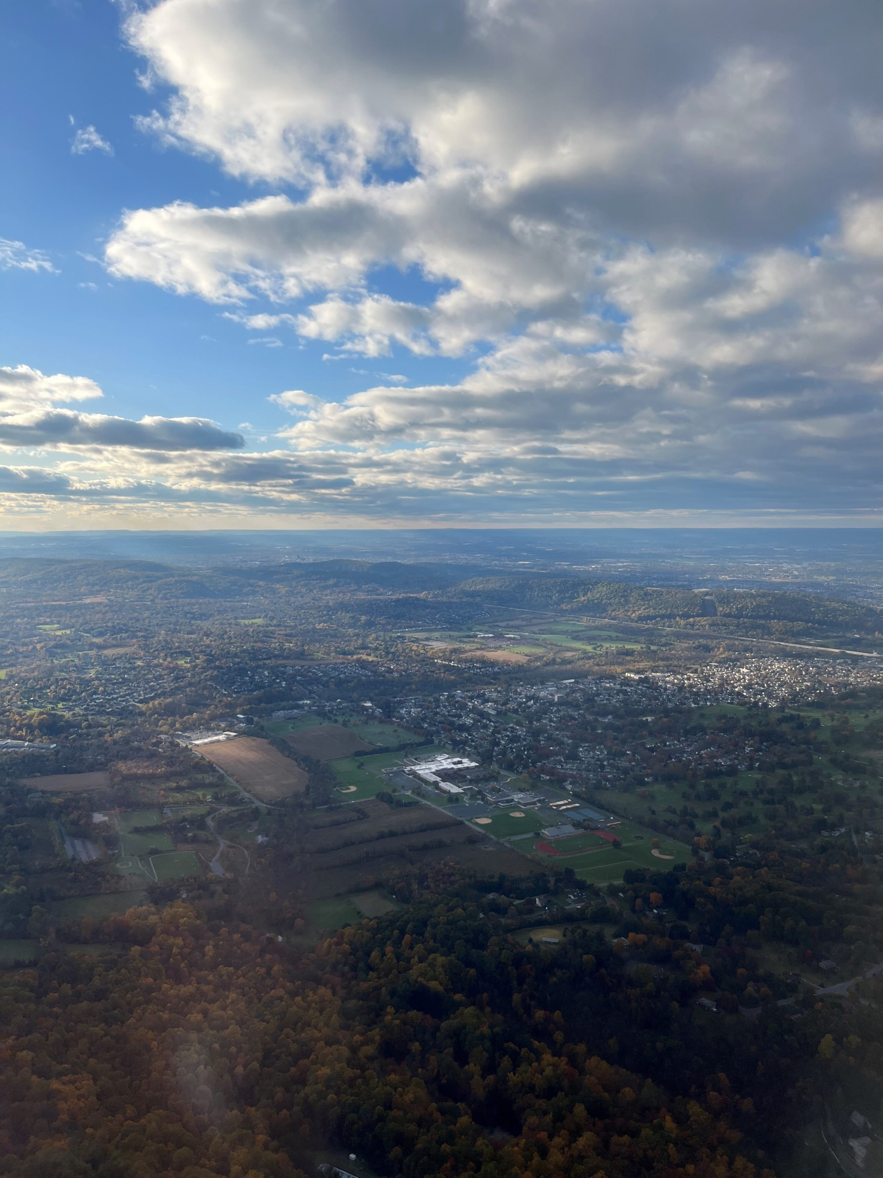 Image from airplane overlooking the Lehigh Valley with clouds in skies and a mix of rural areas and developed cities below.